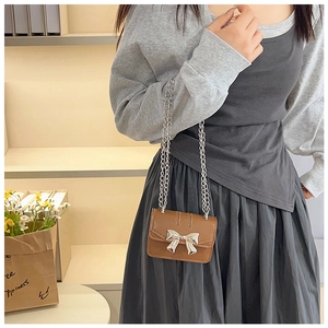 Detail of vintage brown mini crossbody bag with silver bow accent and chain strap