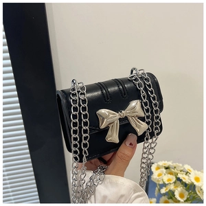 Close-up of black leather mini bag with a large silver bow and metallic chain strap