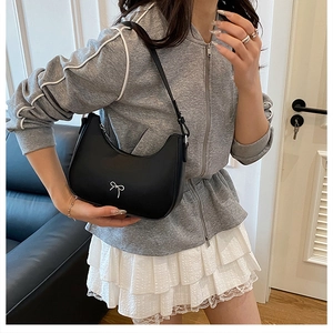 Close-up of black hobo shoulder bag featuring a decorative white bow on the side