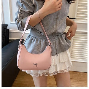 Detail of pink hobo bag featuring a metal bow accent and smooth synthetic leather finish