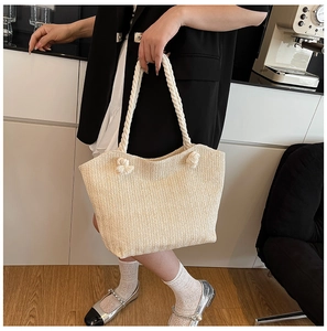 Detail view of woven straw tote bag with braided rope handles in a minimalist indoor setting