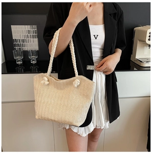 Detail of hand-woven straw tote bag with cream-colored rope handles in a modern setting