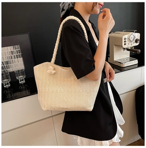 Detail of beige straw tote bag featuring woven herringbone texture and rope handles