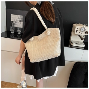 Detail of cream woven tote bag featuring soft cotton rope shoulder straps and knotted accents
