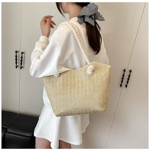 Detail of hand-woven straw tote bag with chunky cotton rope straps on shoulder