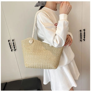 Detail of hand-woven straw tote bag with natural herringbone texture and cotton rope handle