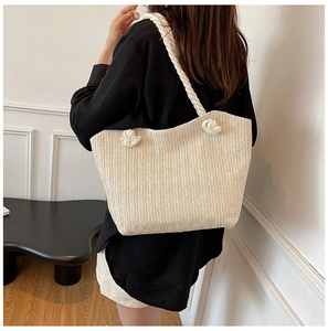 Detail of hand-woven straw tote bag with chunky cotton rope handles and minimalist knot