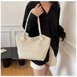 Detail of hand-woven straw tote bag with chunky cotton rope handles and knot accents