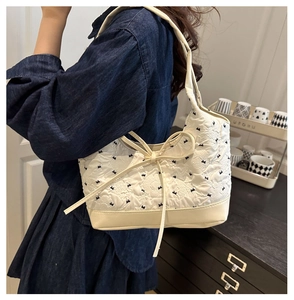 Dettaglio della borsa tote trapuntata bianca con ricamo blu e piccolo fiocco decorativo