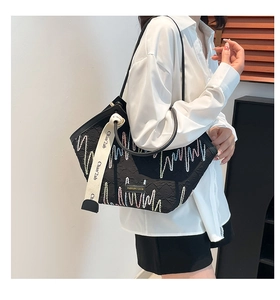 Detail of colorful wave embroidery on black canvas tote bag with woven shoulder strap