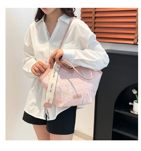 Detail of pink textured tote bag with colorful embroidery and wide slogan strap