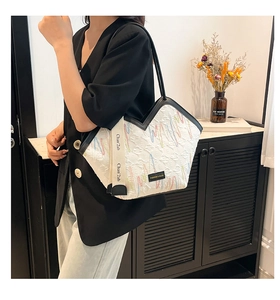 Detail of white tote bag featuring rainbow wavy embroidery and textured square embossing