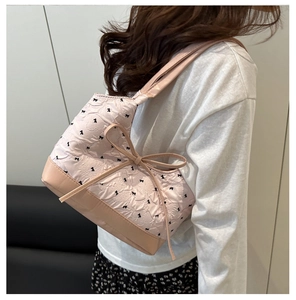 Détail du sac à bandoulière rose avec imprimé nœud et ruban 3D sur tissu plissé