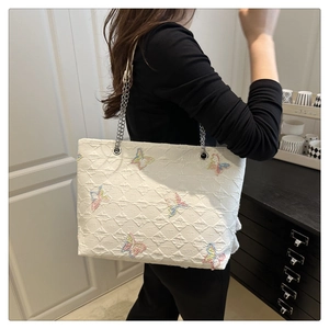 Detail of white tote bag with embossed rhombus texture and colorful butterfly embroidery