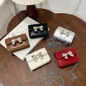 Mini crossbody chain bag with bow knot in five colors on dark wood table