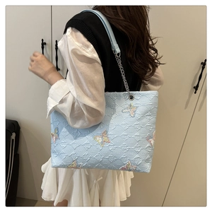 Detail of light blue tote bag featuring seersucker texture and butterfly embroidery