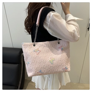 Detail of pink quilted tote bag with colorful butterfly embroidery and chain strap