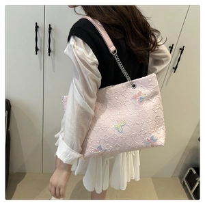Detailed close-up of pink quilted tote bag with rainbow butterfly embroidery and chain strap