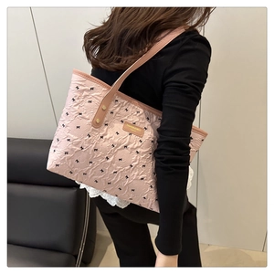 Detailed close-up of pink quilted tote bag with floral texture and black mini bows