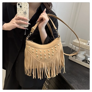 Detail of bohemian crescent shoulder bag with suede tassels and gold metal studs