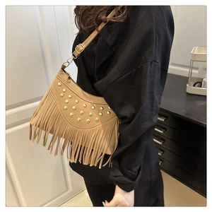 Detail of camel suede saddle bag featuring golden rivets and long fringe tassels