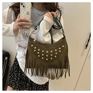 Detailed macro view of vintage brown suede bag with gold rivets and long fringe accents