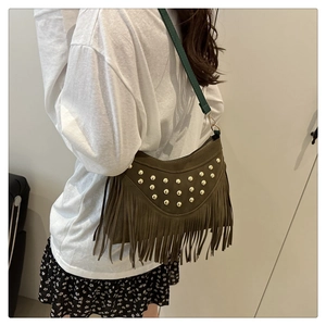Close-up of green suede crossbody bag with gold studs and long vintage fringe details