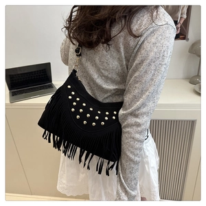 Close-up of black fringe crescent bag with gold rivets and suede-like texture