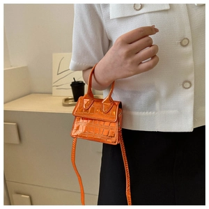 Mini orange crocodile pattern bag with glossy finish shown on model's outfit
