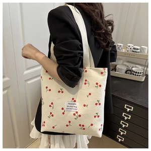 Close-up of corduroy tote bag featuring red cherry prints and wide shoulder strap