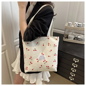Detail of corduroy tote bag with cherry print and wide shoulder strap on model