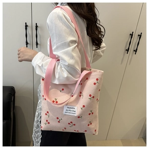 Close-up of pink corduroy tote bag featuring red cherry embroidery and stylish text label