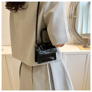 Detail of black faux crocodile leather mini bag with gold hardware and top handle