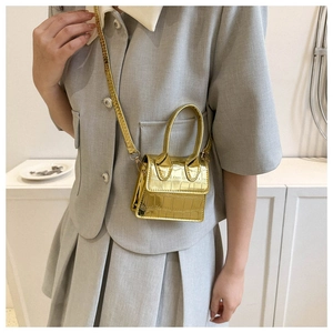 Detail view of gold crocodile pattern mini bag with chic chain strap worn by a model