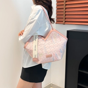 Pink textured tote bag with wave embroidery and printed strap shown on a model
