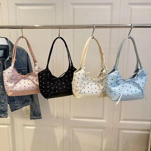 Borse tote con fiocco in rosa, nero, beige e blu appese su un espositore
