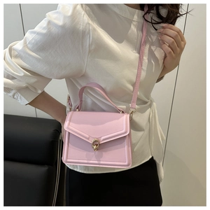 Sac bandoulière en similicuir rose avec rabat en V et fermoir doré porté par un mannequin