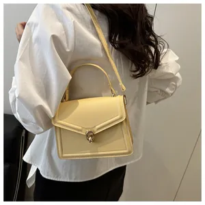 Detail of cream PU leather crossbody bag with gold V-shaped trim and metal lock closure