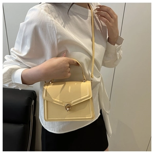 Detail of light yellow crossbody square bag with gold twist lock and leather texture