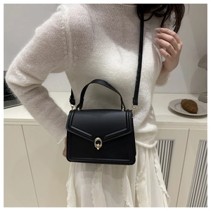 Detail view of black V-flap leather crossbody bag with elegant gold circular buckle