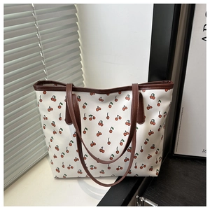 Detail of white tote bag with cherry print pattern and contrast brown leather trim