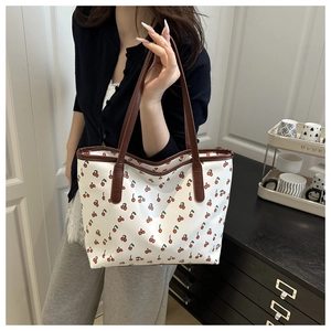 Detail of printed tote bag with cherry pattern and contrasting brown leather handles
