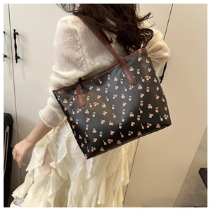 Close-up of printed tote bag with cherry pattern and brown faux leather shoulder straps