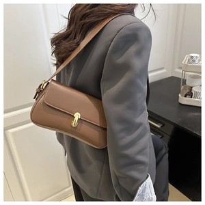 Brown leather underarm bag with gold buckles shown on model from back view