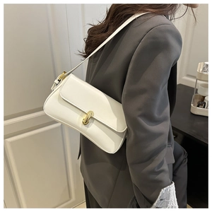 Side view of white leather underarm bag with gold U-shaped clasp on grey blazer suit