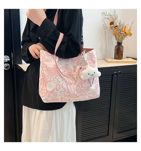 Détail d'un sac cabas graffiti avec un pendentif en peluche nuage blanc mignon