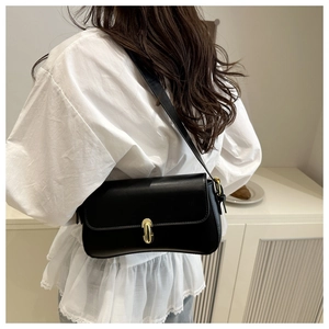 Rear view of minimalist black shoulder bag with gold clasp shown on a model
