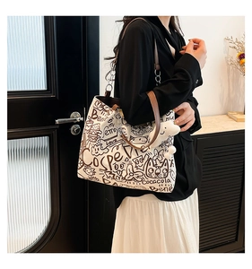 Détail du sac cabas en toile avec imprimé graffiti, anses en cuir et pendentif peluche