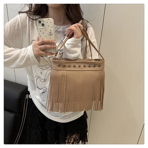 Selfie miroir montrant un sac à main à franges marron clair avec des rivets et du cuir grainé
