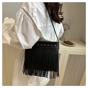 Détail du sac à bandoulière noir à franges avec clous argentés et cuir grainé